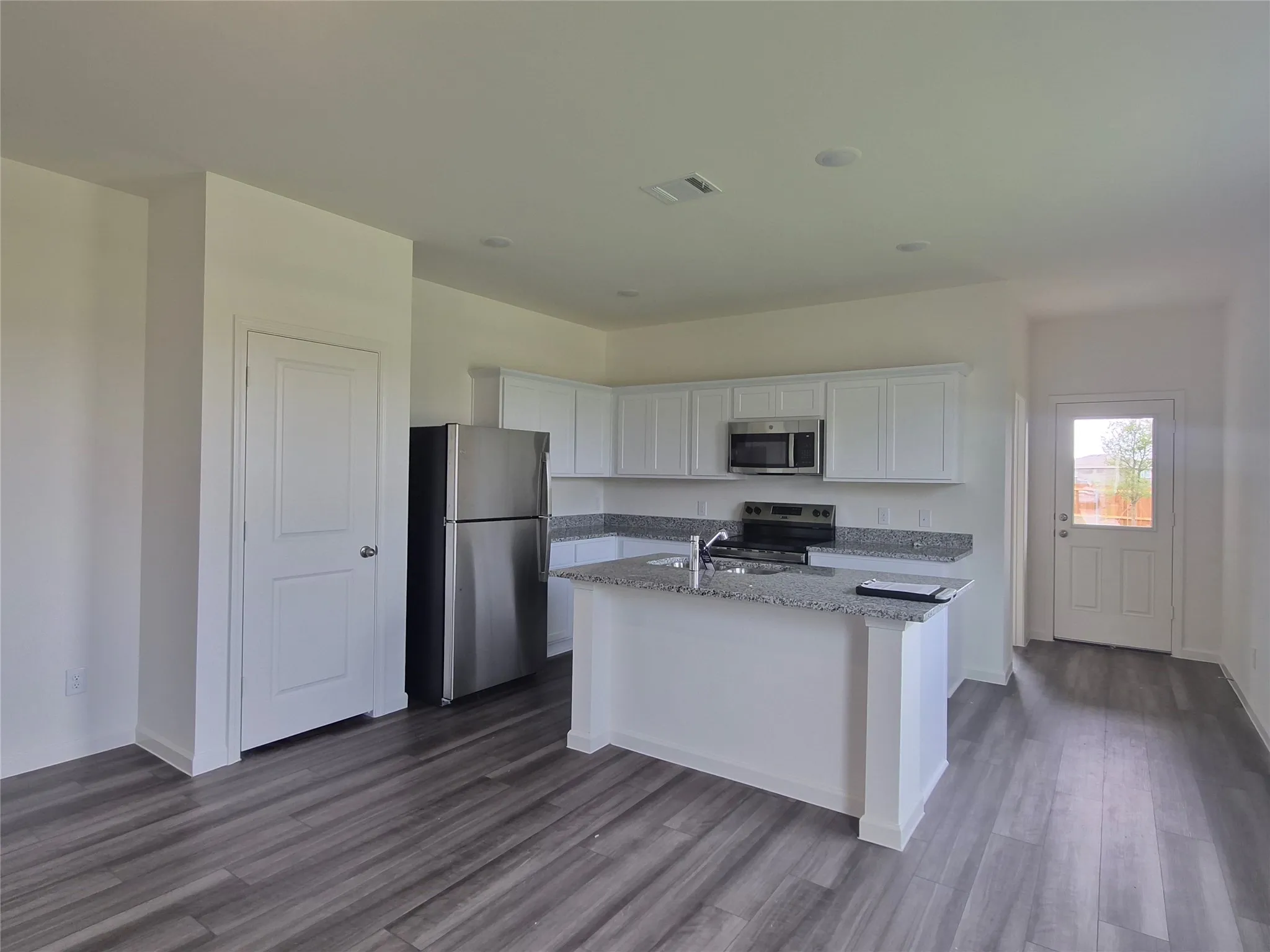 Kitchen featuring white cabinetry, granite countertops, stainless steel appliances, and wood-finish flooring