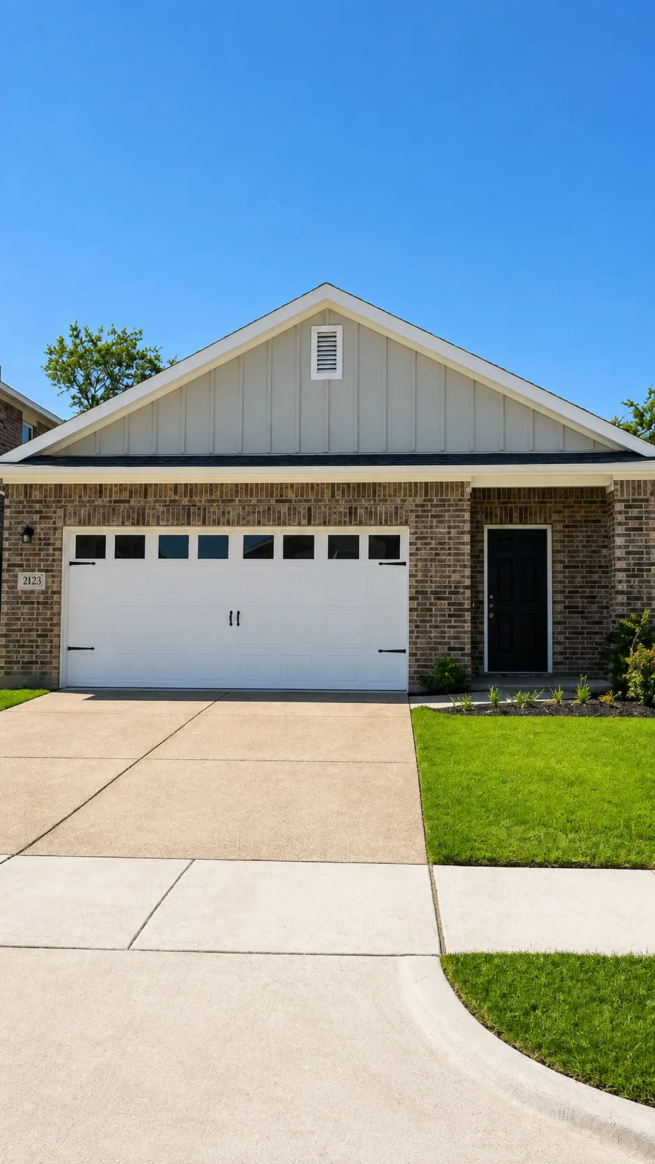 Brick exterior with a peaked roofline, board and batten siding, and an attached garage with windows