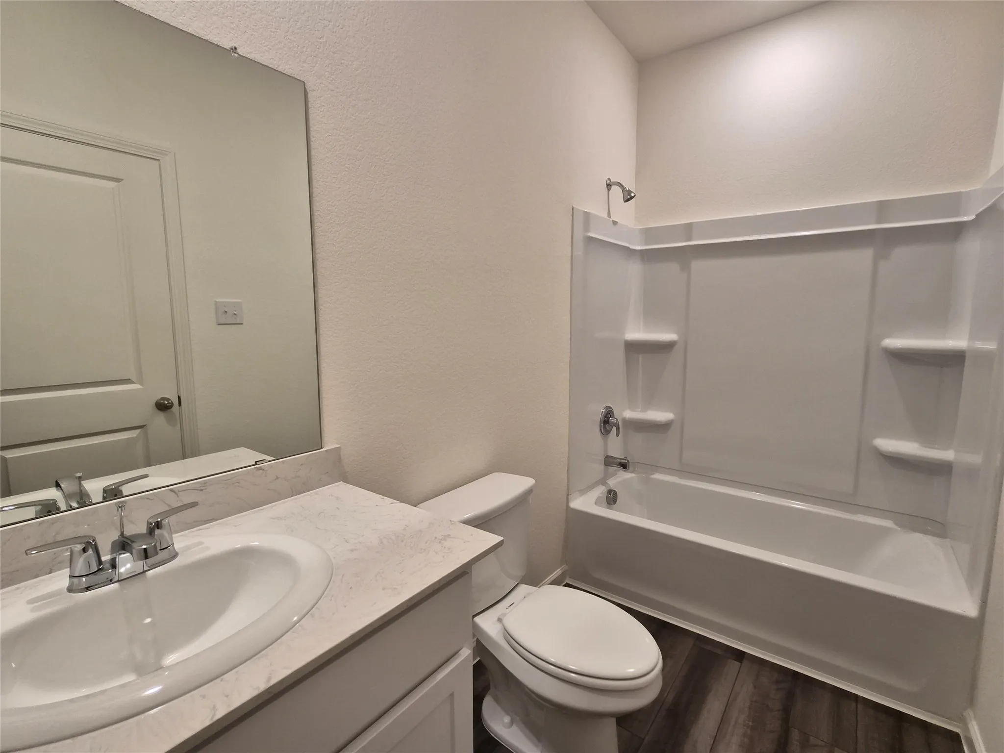 Bathroom with a white vanity, integrated sink, chrome faucet, and expansive wall mirror