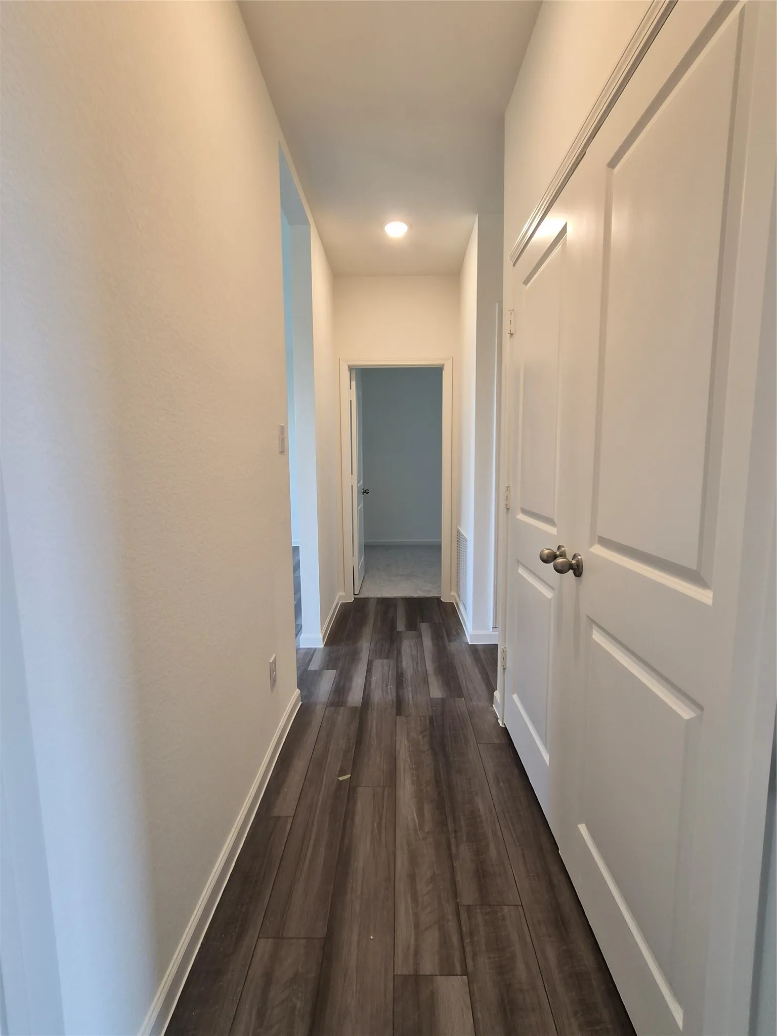 Wood-finish flooring throughout, bright white walls, recessed ceiling light, and panel doors with satin nickel hardware