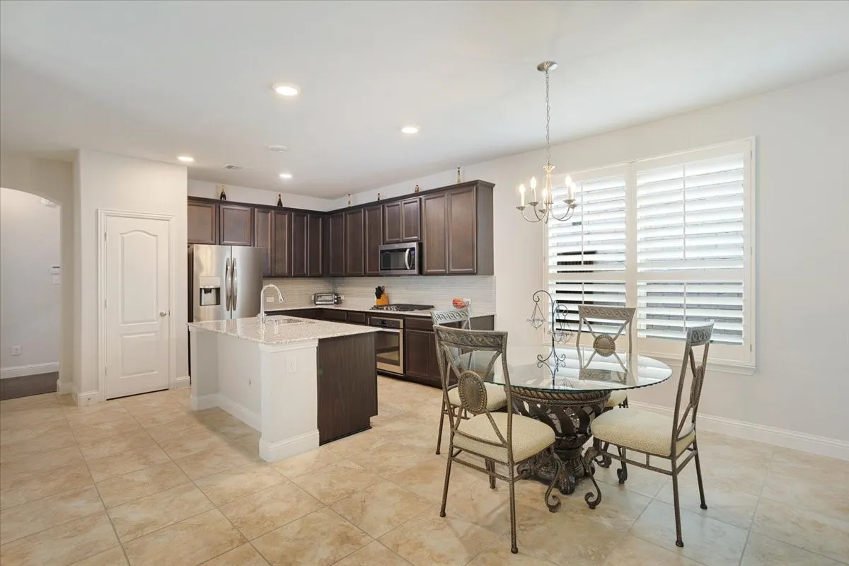 Kitchen featuring dark wood cabinetry, a center island with a light-toned countertop, stainless steel appliances, and recessed lighting