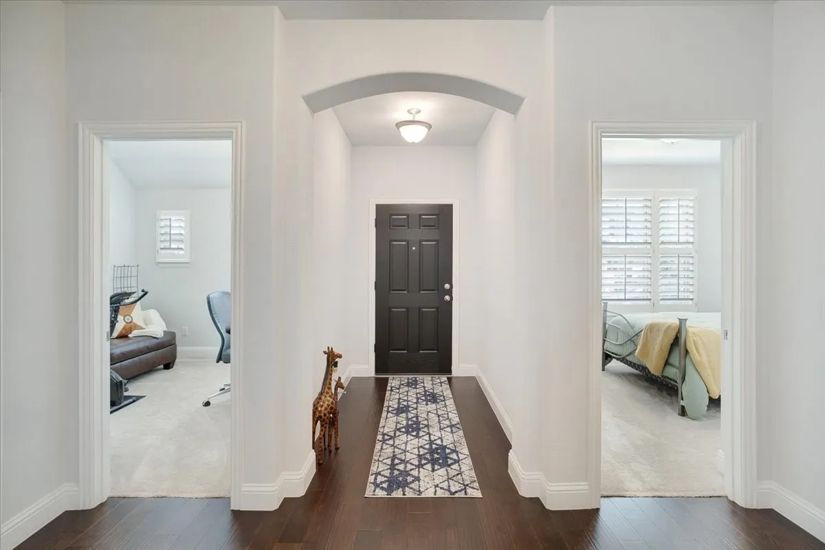 Hallway featuring dark wood-finish flooring, an arched entryway, and a panel-style front door