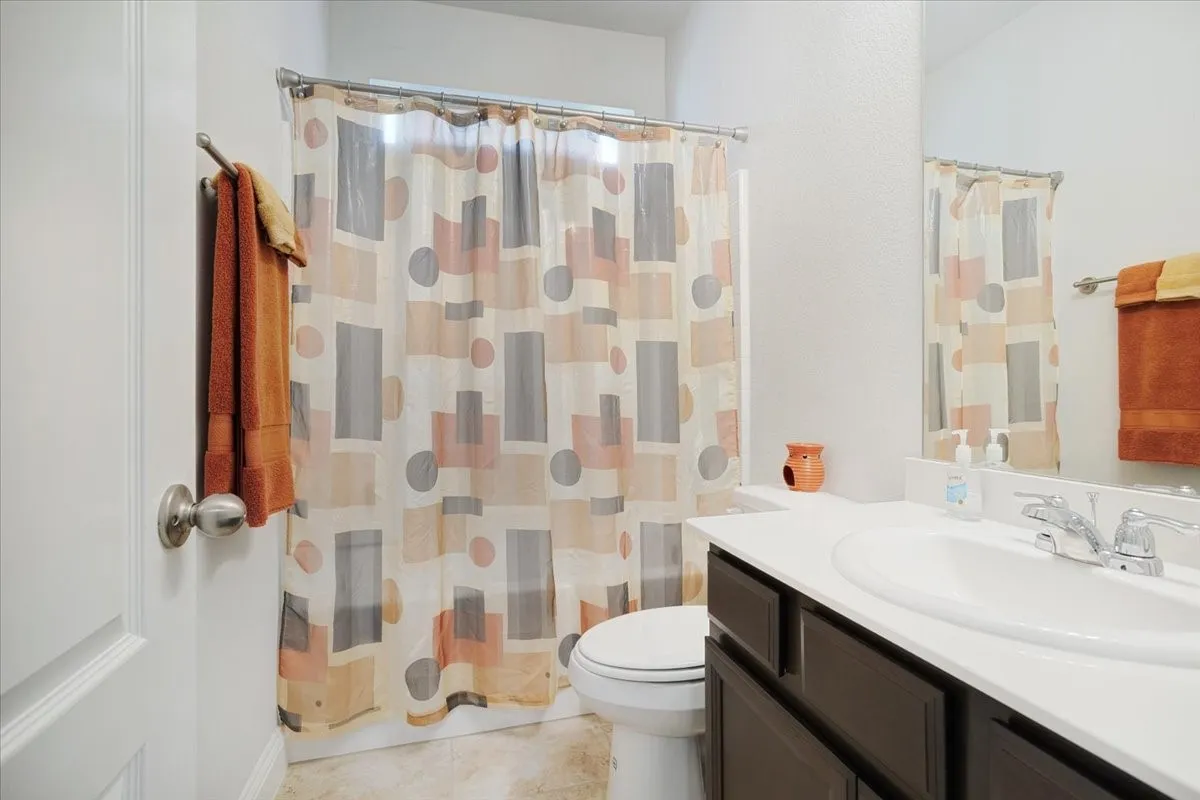 Spa-inspired bathroom featuring a dark wood vanity with dual-sink configuration, white countertop, and chrome fixtures