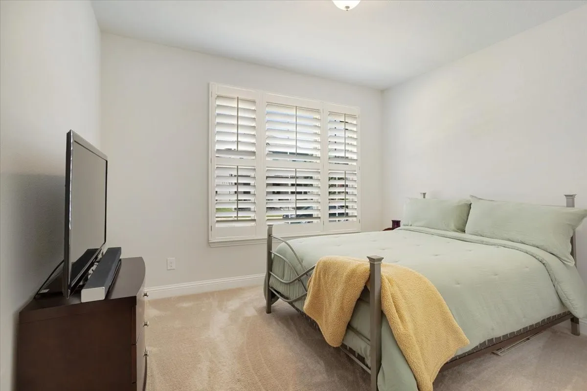 Window with plantation shutters, ceiling-mounted light fixture, and neutral wall color