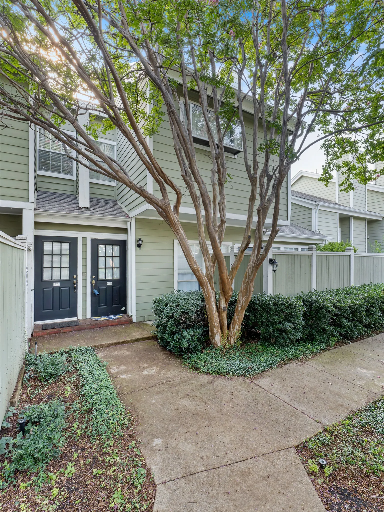 Siding exterior with multiple windows, complemented by mature trees and landscaping