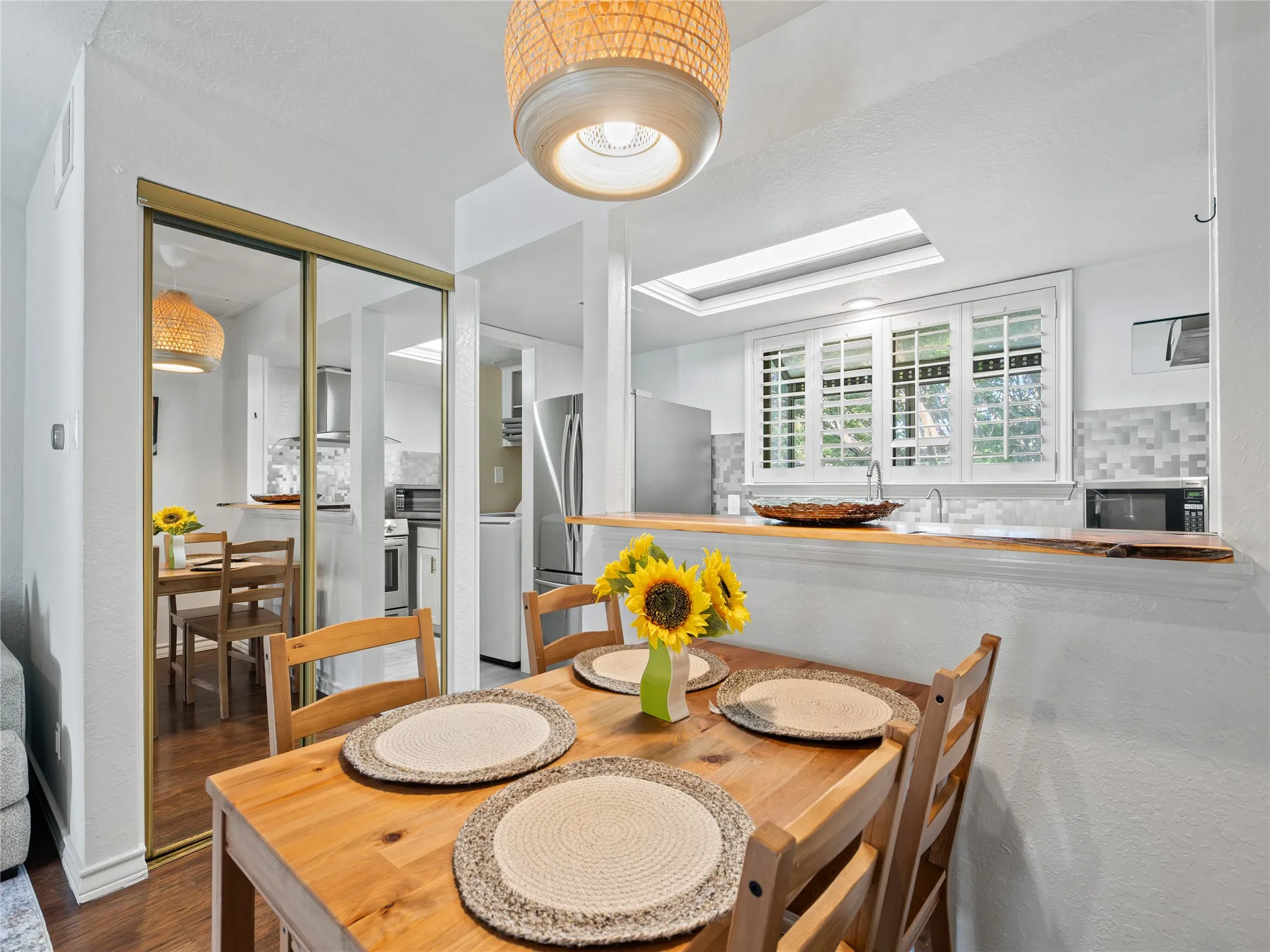 Dining area with wood-finish flooring, a woven pendant light fixture, and mirrored closet doors