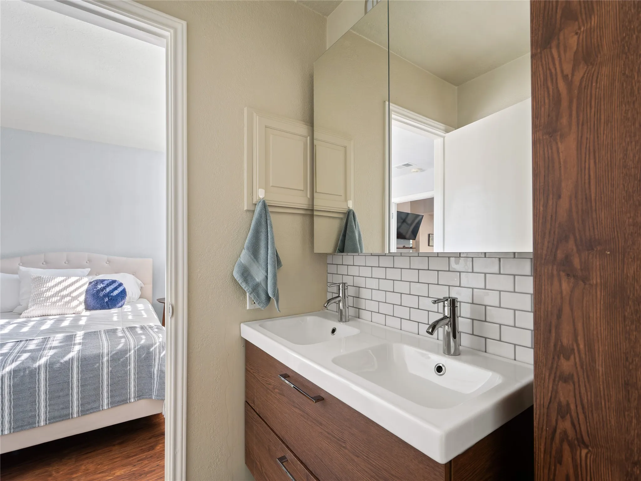 Dual rectangular undermount sinks, wood-finish vanity with two drawers, subway tile backsplash, and mirrored medicine cabinet