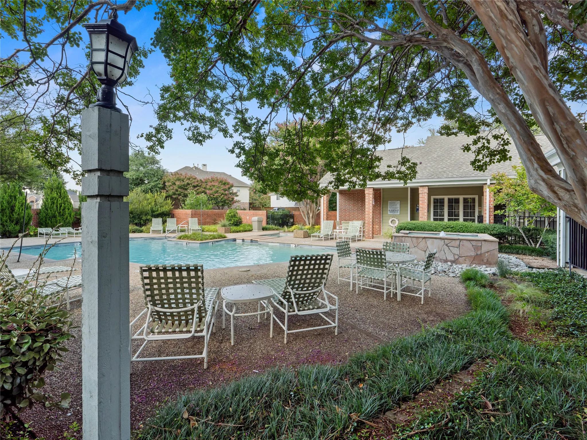 Swimming pool with adjacent spa, surrounded by a gravel patio and established landscaping