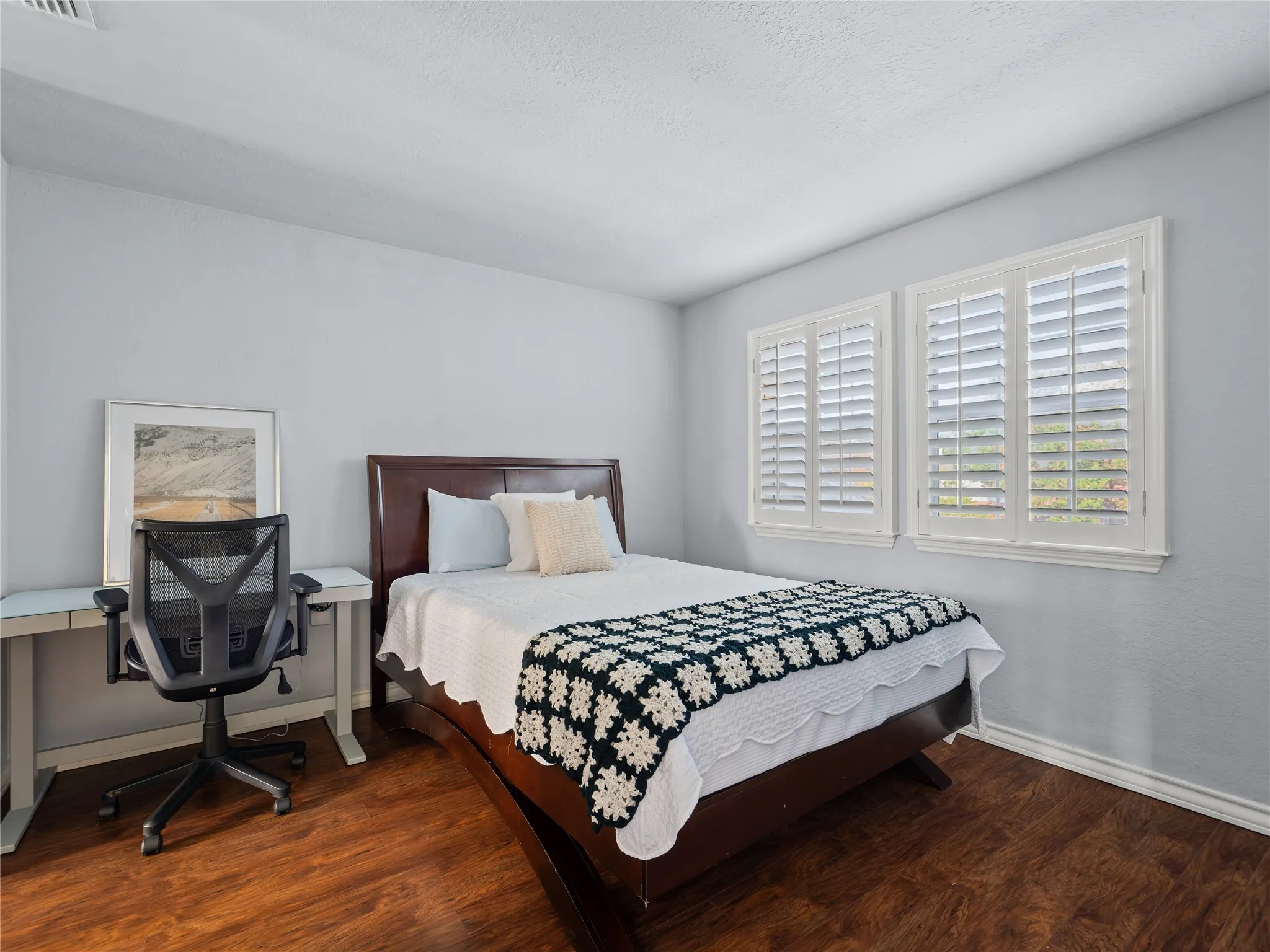Wood-finish flooring, white walls, and dual windows with plantation shutters