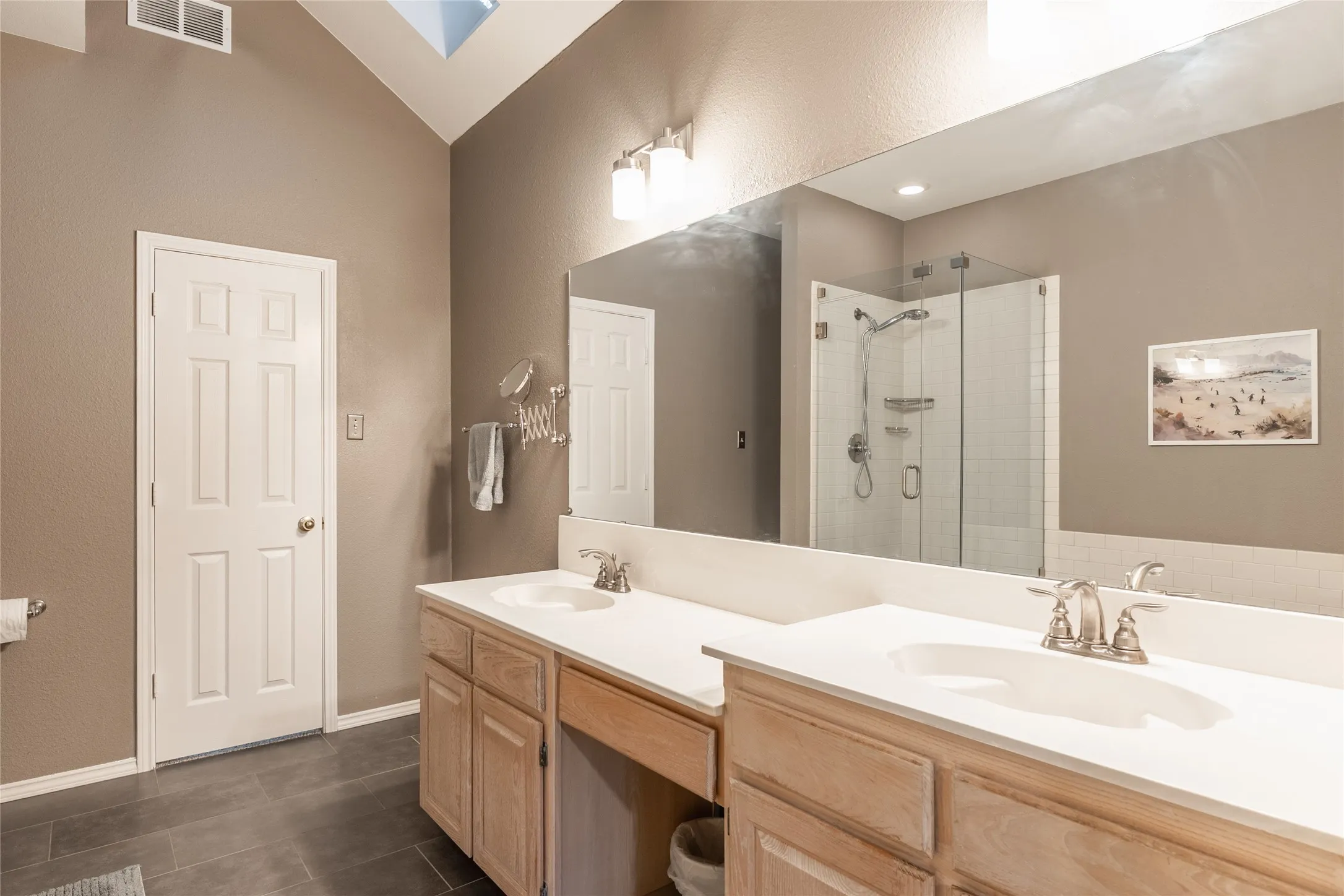 Dual vanity with integrated sinks, light wood-finish cabinetry, and a full-width mirror