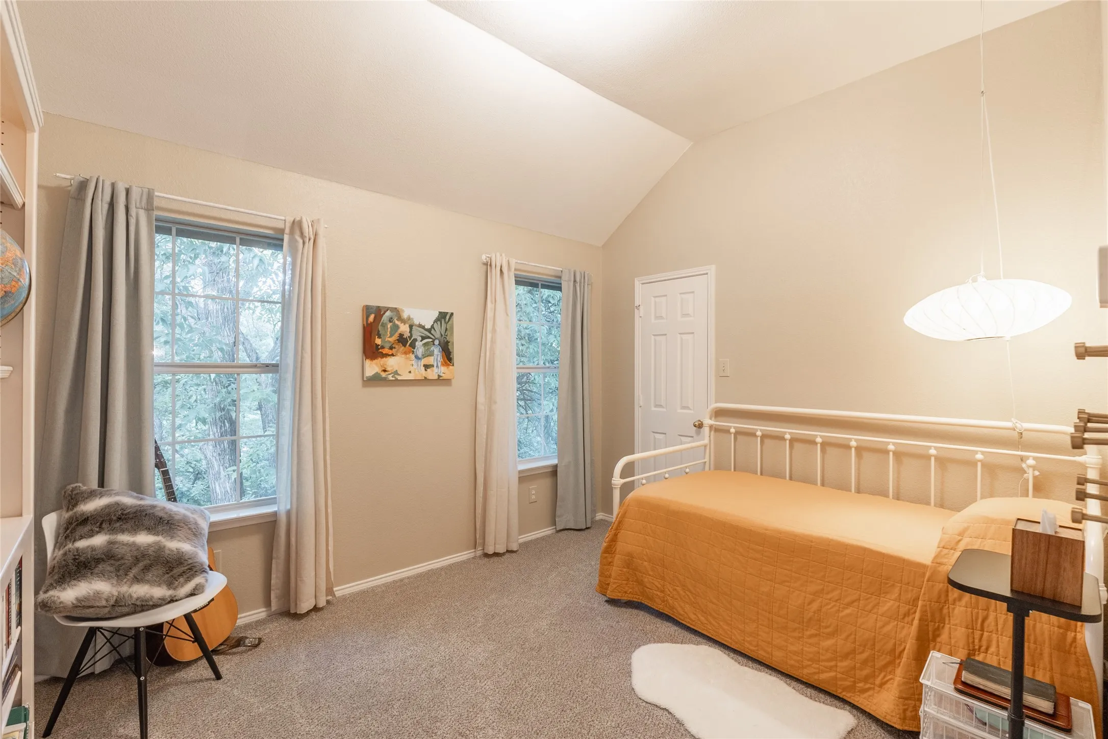 Vaulted ceiling with an attached pendant light fixture, carpeted flooring, and two windows