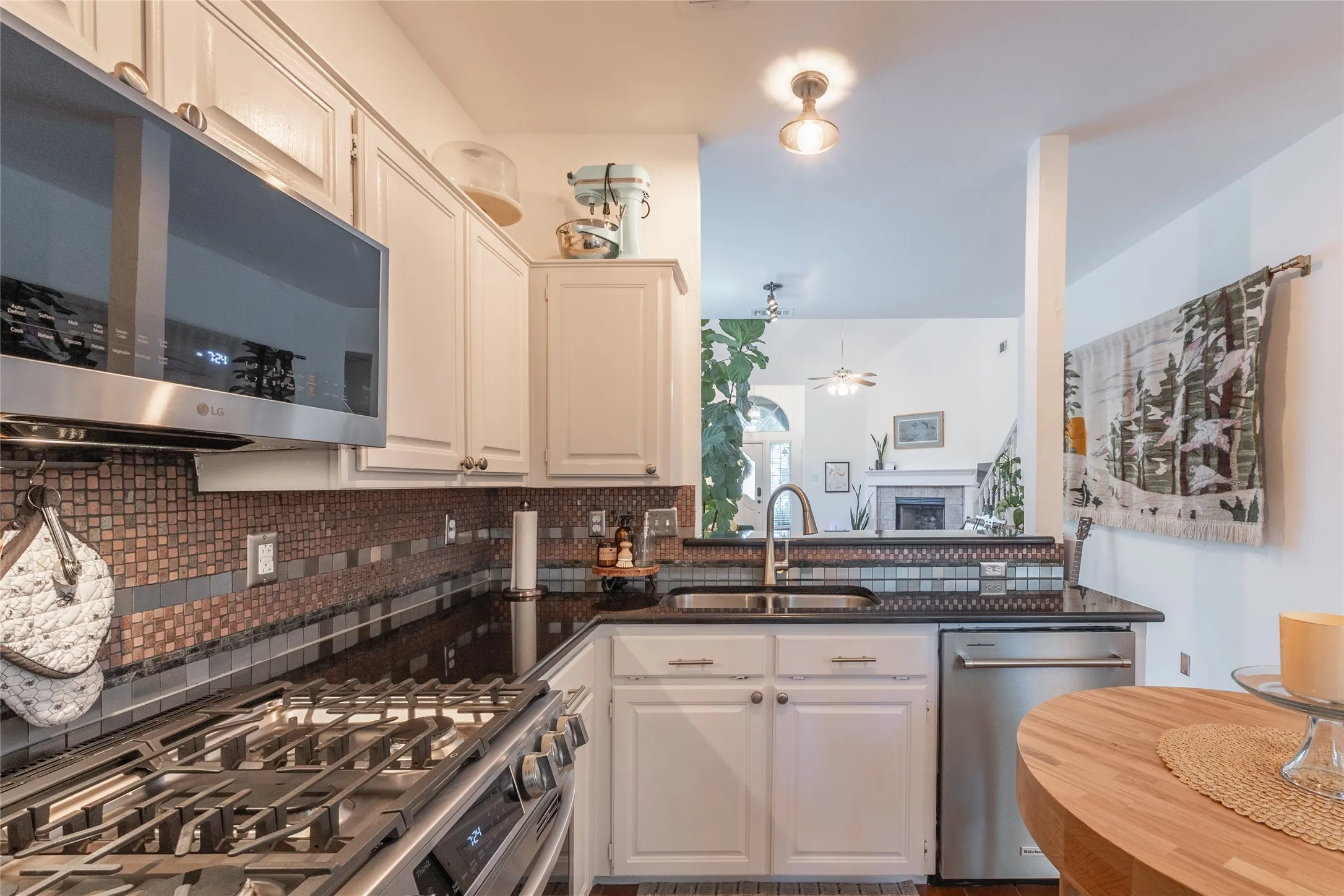 Kitchen featuring white cabinetry, black countertops, a mosaic tile backsplash, stainless steel appliances, and a built-in​​‌​​​​‌​​‌‌​‌‌​​​‌‌​‌​‌​‌​​​‌​​ sink