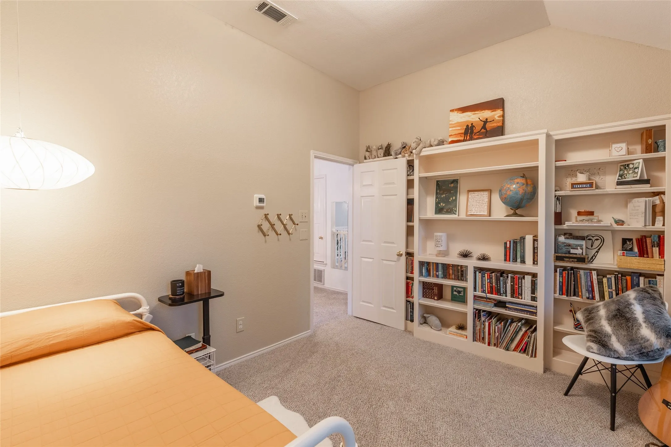 Vaulted ceiling, built-in shelving, carpet flooring, interior door, wall-mounted light fixture