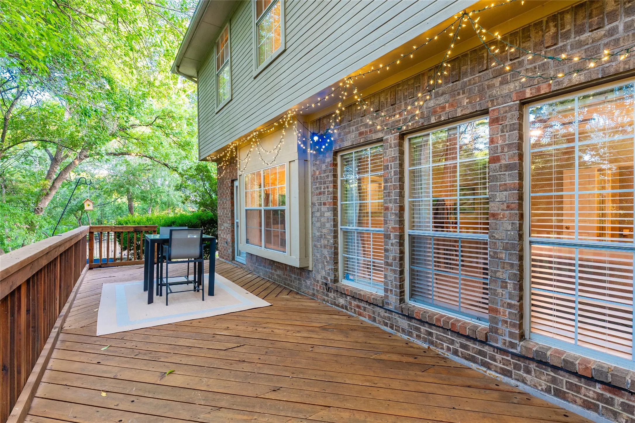 Expansive wood deck with a wood railing and brick facade