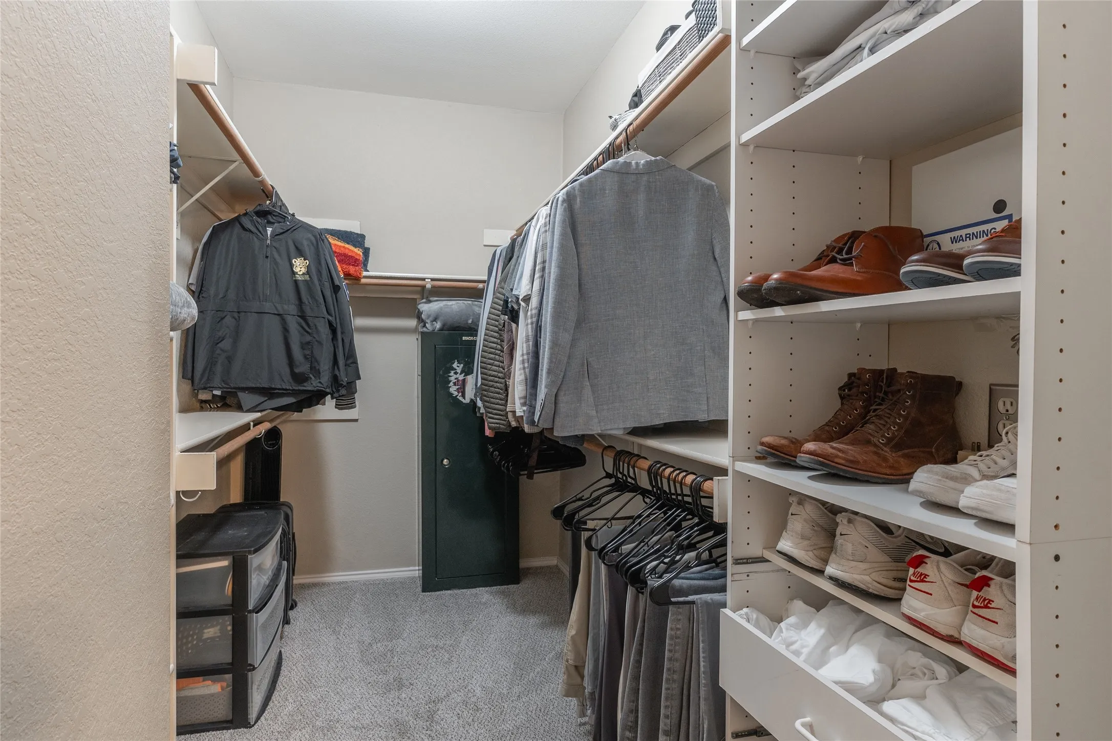 Walk-in closet featuring built-in shelving, multiple hanging rods, and soft gray carpeting