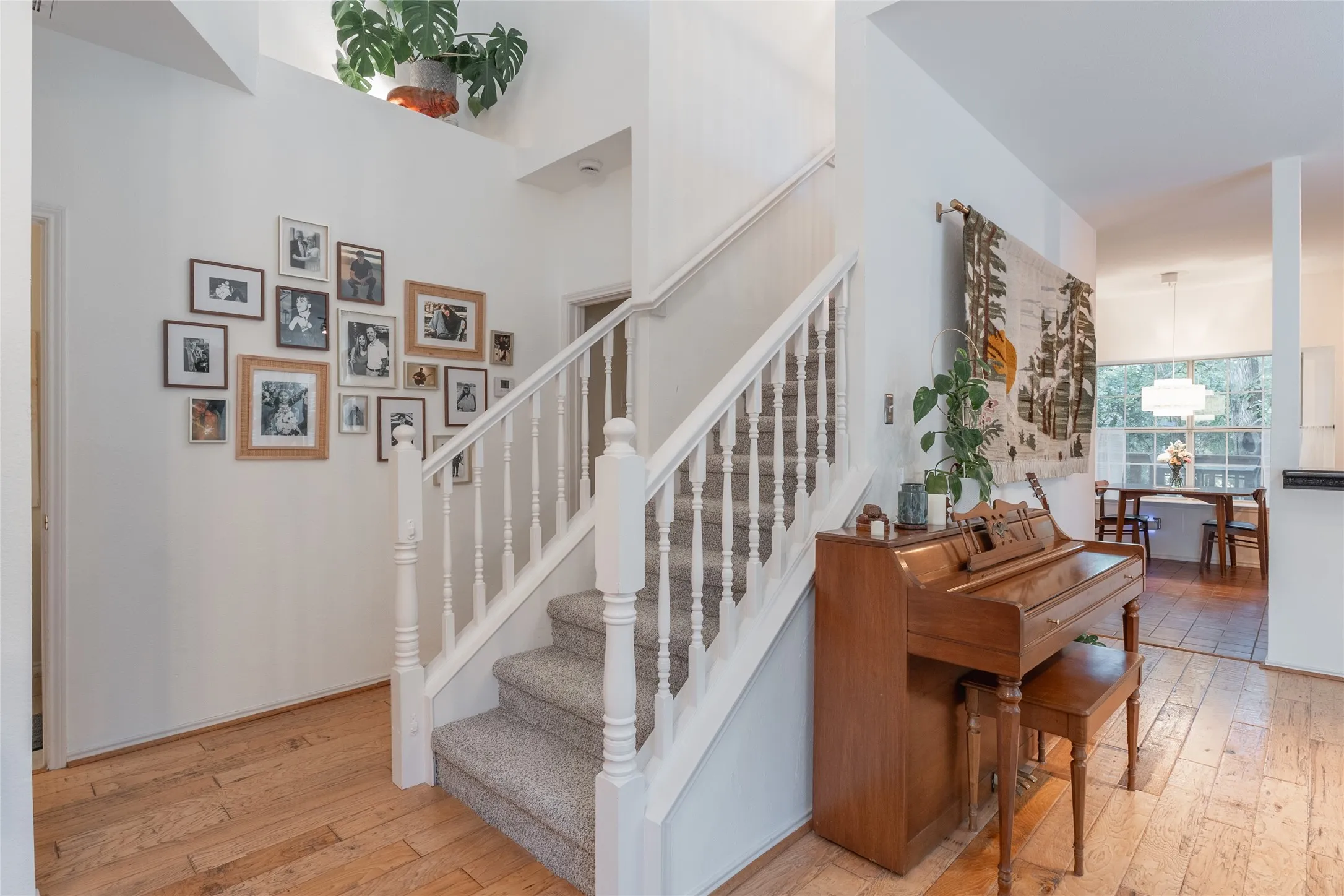 Wood-finish flooring, staircase with carpeted treads and white wood balusters, and a vaulted ceiling