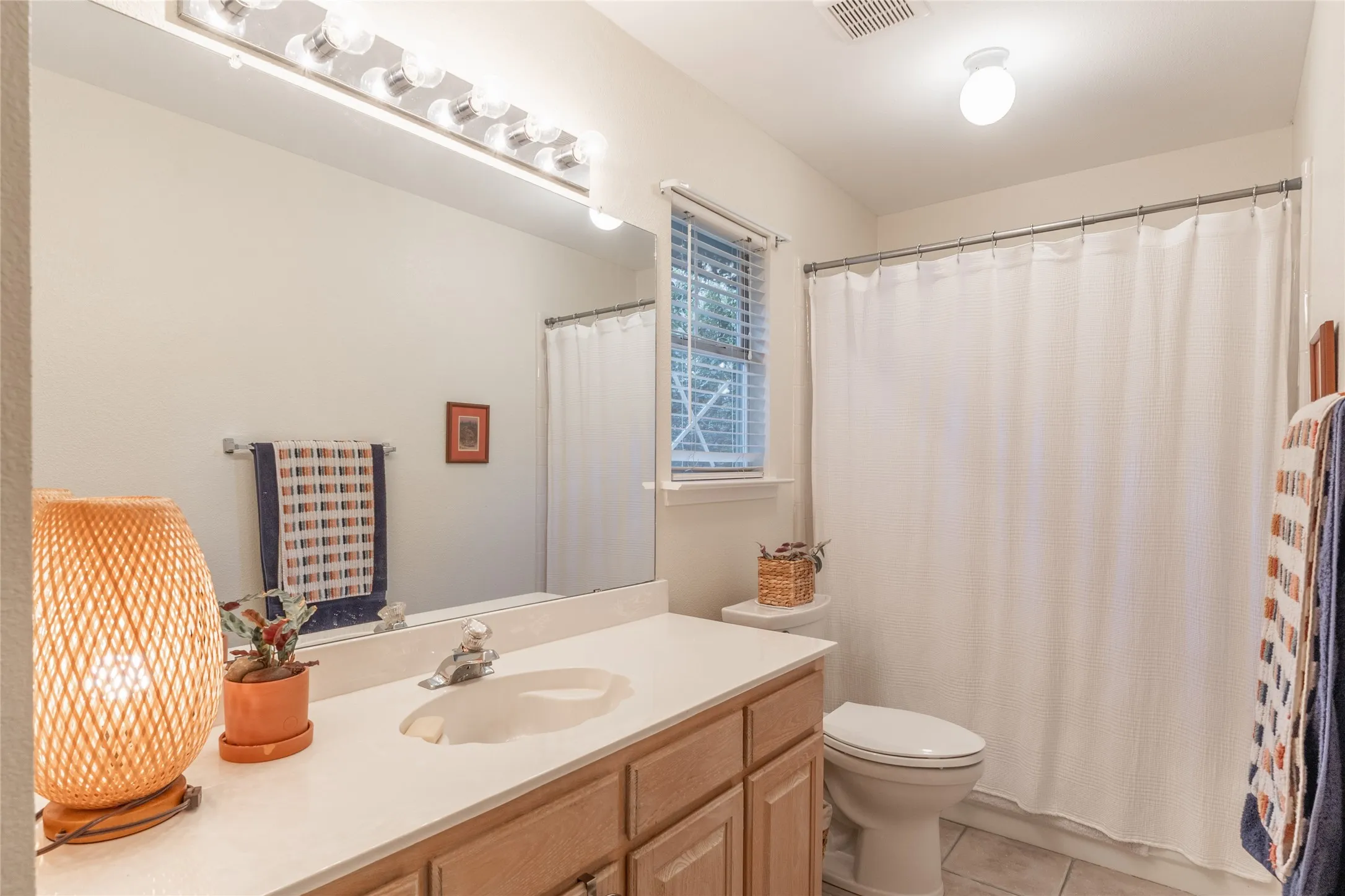 Vanity with integrated sink, wood-finish cabinetry, and a full-width mirror