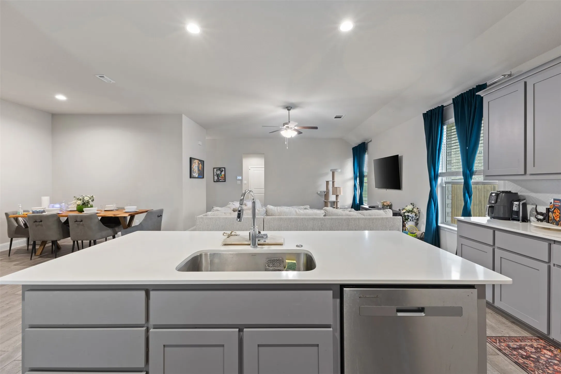 Kitchen island with an undermount sink, a stainless steel dishwasher, and light gray cabinetry
