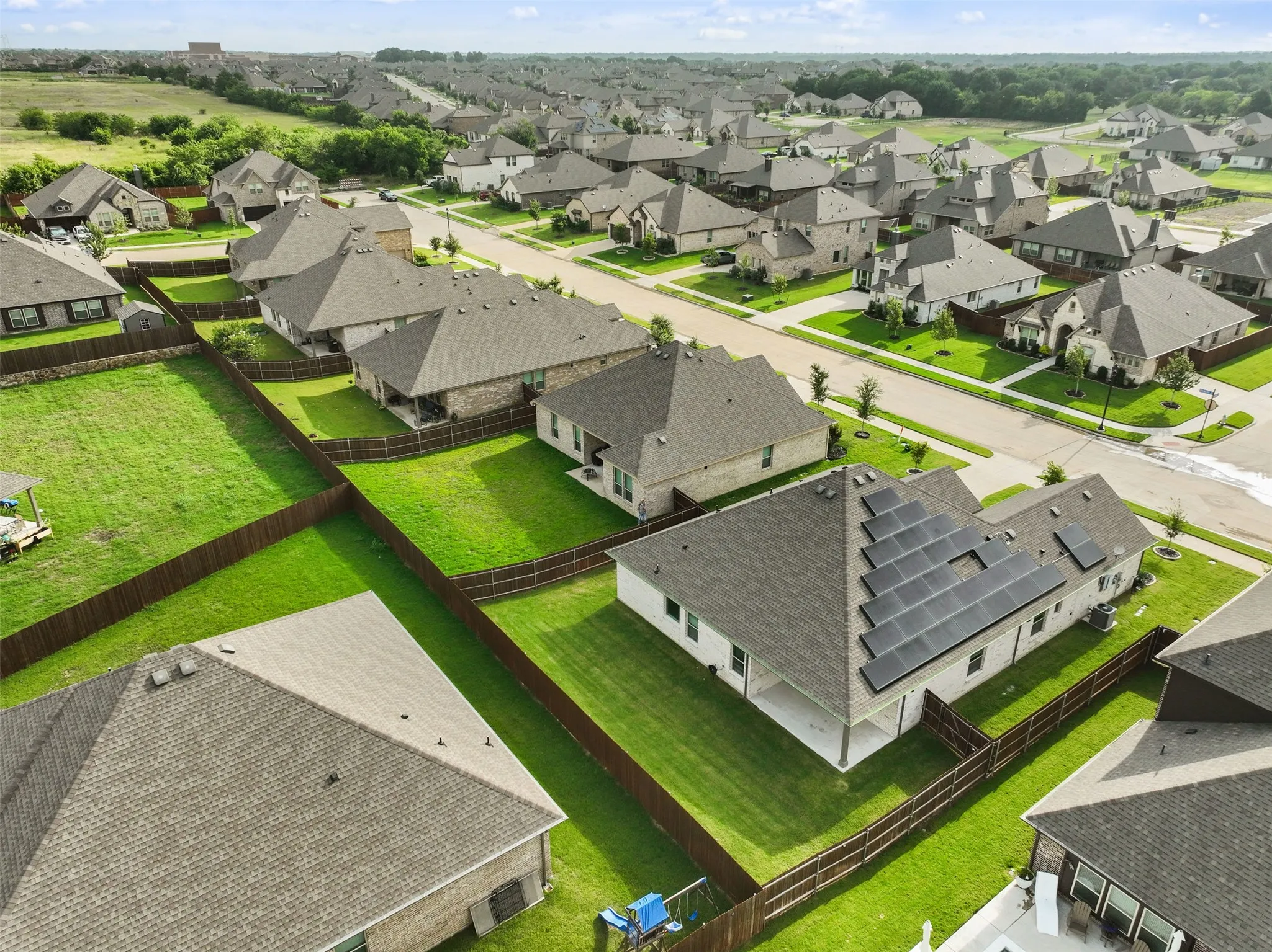 Rooftop solar panels, covered patio, fenced backyard, and a brick exterior