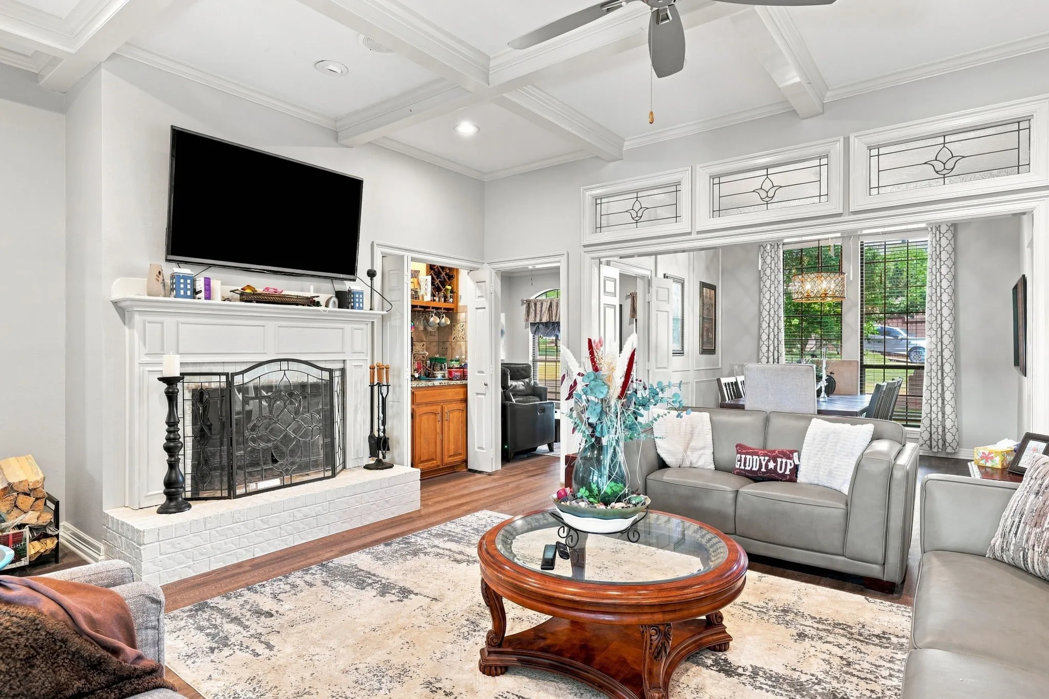 Living area featuring a white brick fireplace with a mantel, wood-finish flooring, and a coffered ceiling