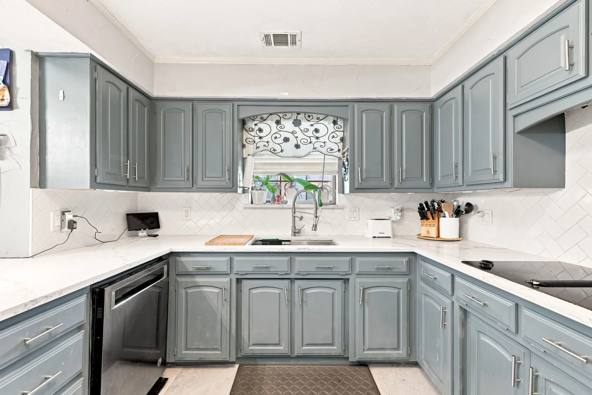 U-shaped kitchen featuring grey cabinetry, white countertops, stainless steel dishwasher, and white subway tile backsplash