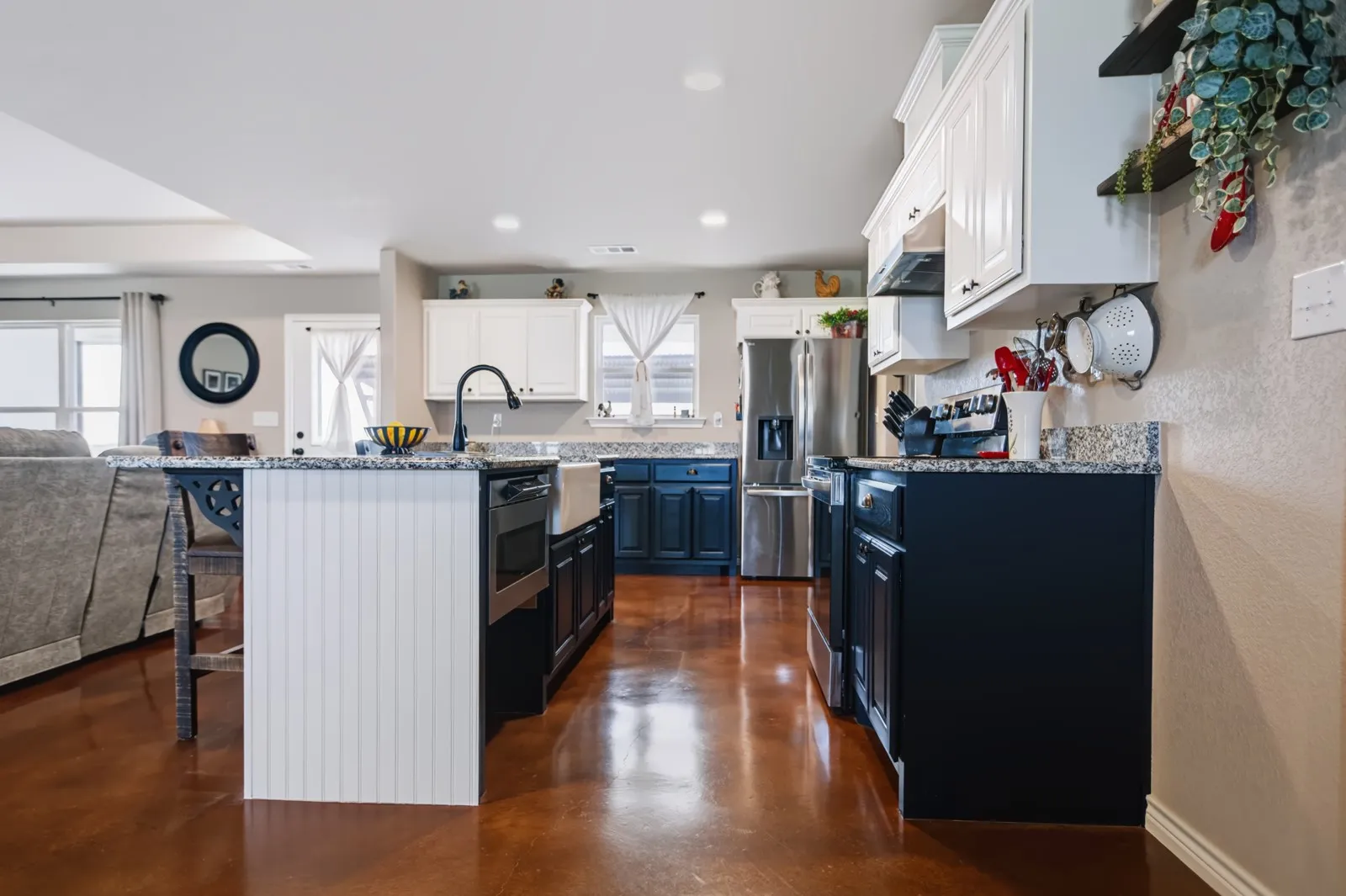 Kitchen with two-tone cabinetry, a central island, a farmhouse sink, stainless steel appliances, and a wood-finish floor