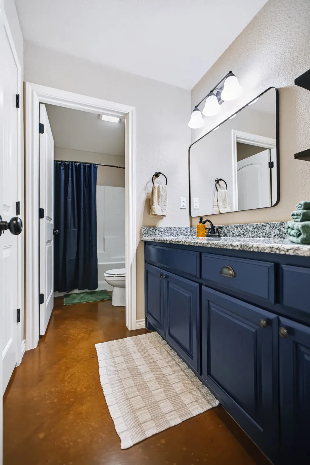 Guest Bathroom
Bathroom featuring a dark blue vanity, speckled countertop, rectangular wall mirror, and dedicated lighting fixture