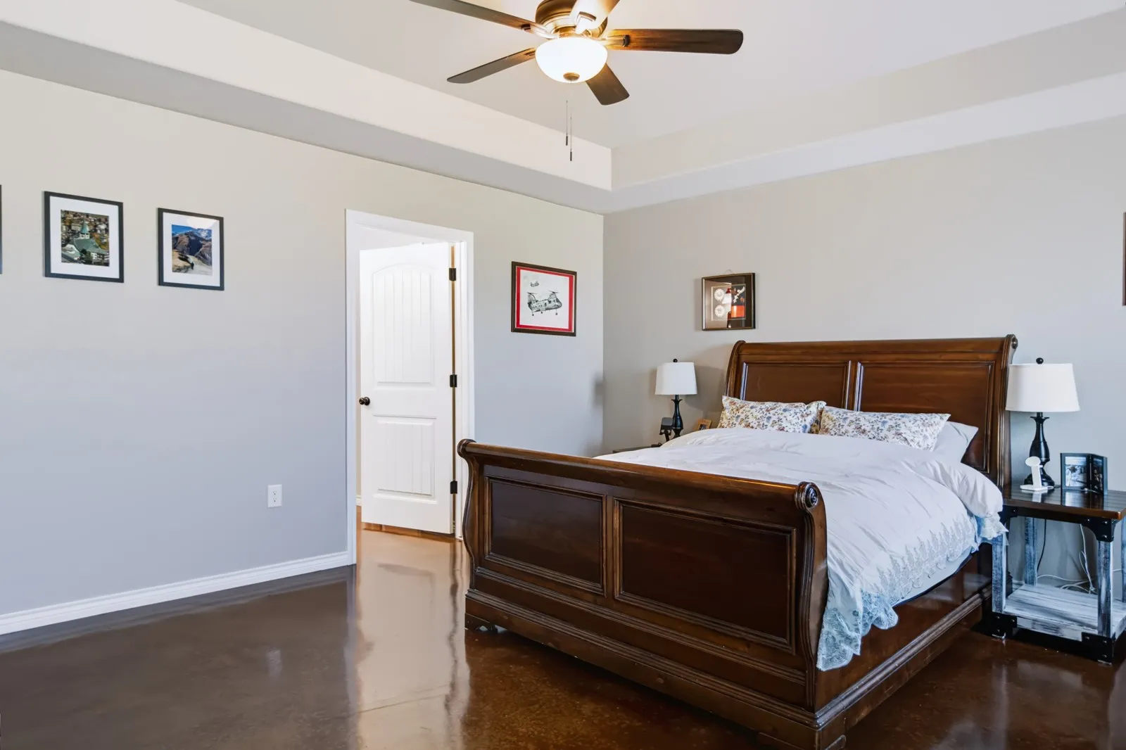 
Tray ceiling with a ceiling fan light fixture, white interior door, and dark wood-finish flooring