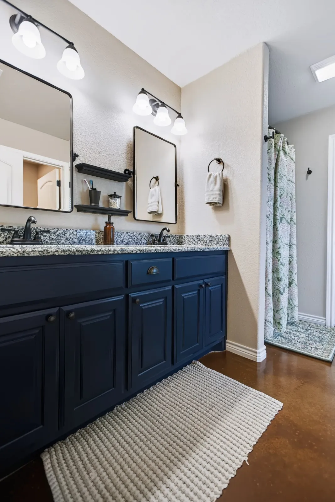 Double vanity with dark blue cabinetry and granite countertops