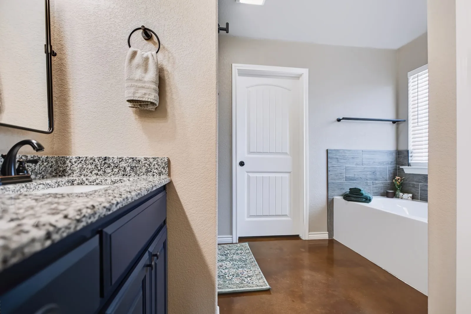 Bathroom featuring a white bathtub, tiled wainscoting, and wood-finish flooring