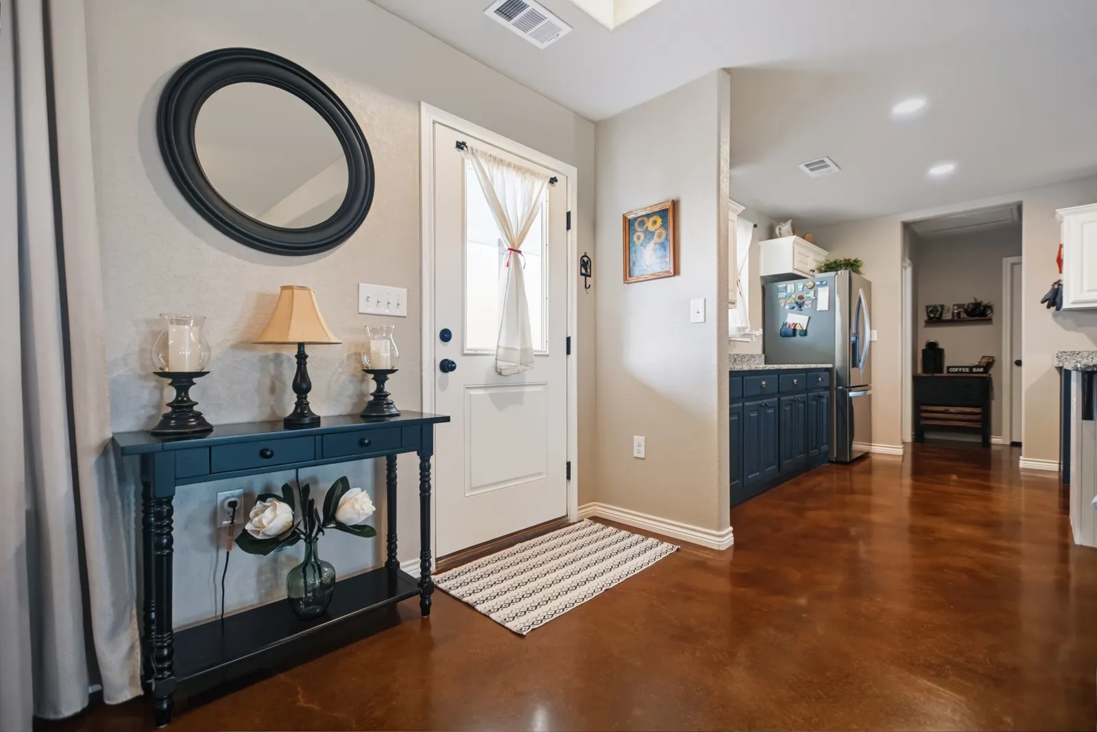 Back Door
Richly toned flooring extends throughout, complemented by a white entry door, recessed lighting, and a kitchen featuring dark-toned cabinetry and light-toned countertops