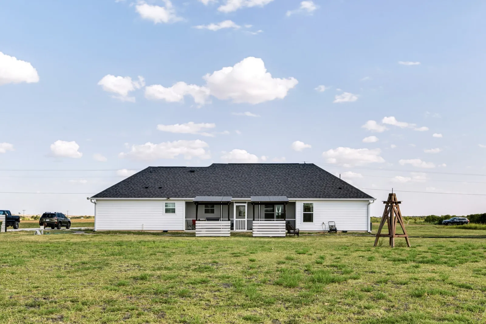 Rear exterior featuring white horizontal siding, dark shingle roof, and a covered patio