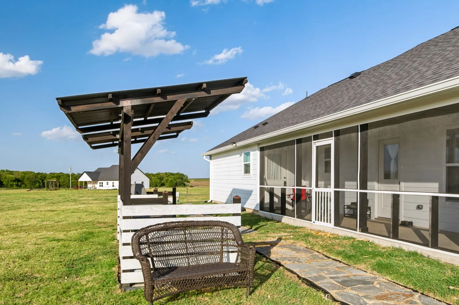 Expansive green space featuring a screened-in porch, patio with a wood pergola, and flagstone pathway
