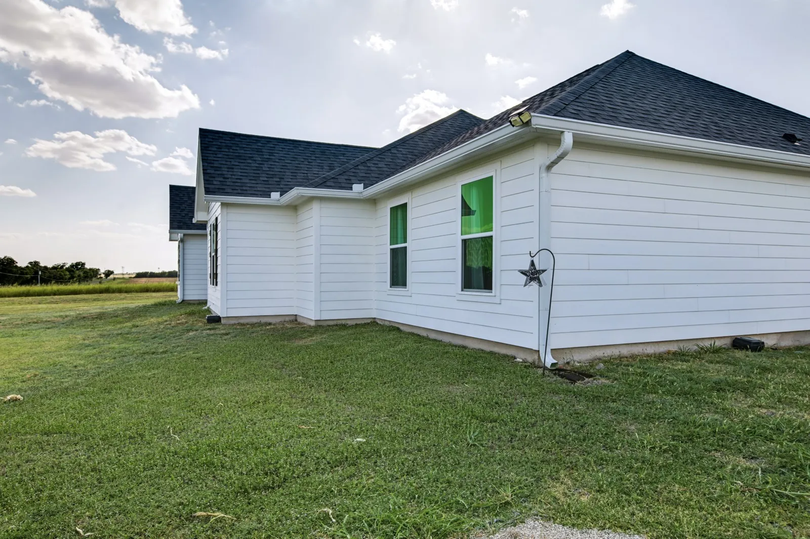 White siding exterior with a dark shingle roof and white gutters