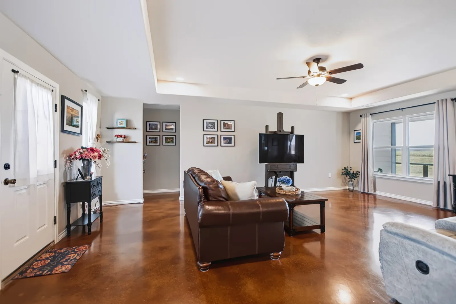 Tray ceiling with recessed lighting, ceiling fan, wood-finish flooring, white trim, and a window with a white sill