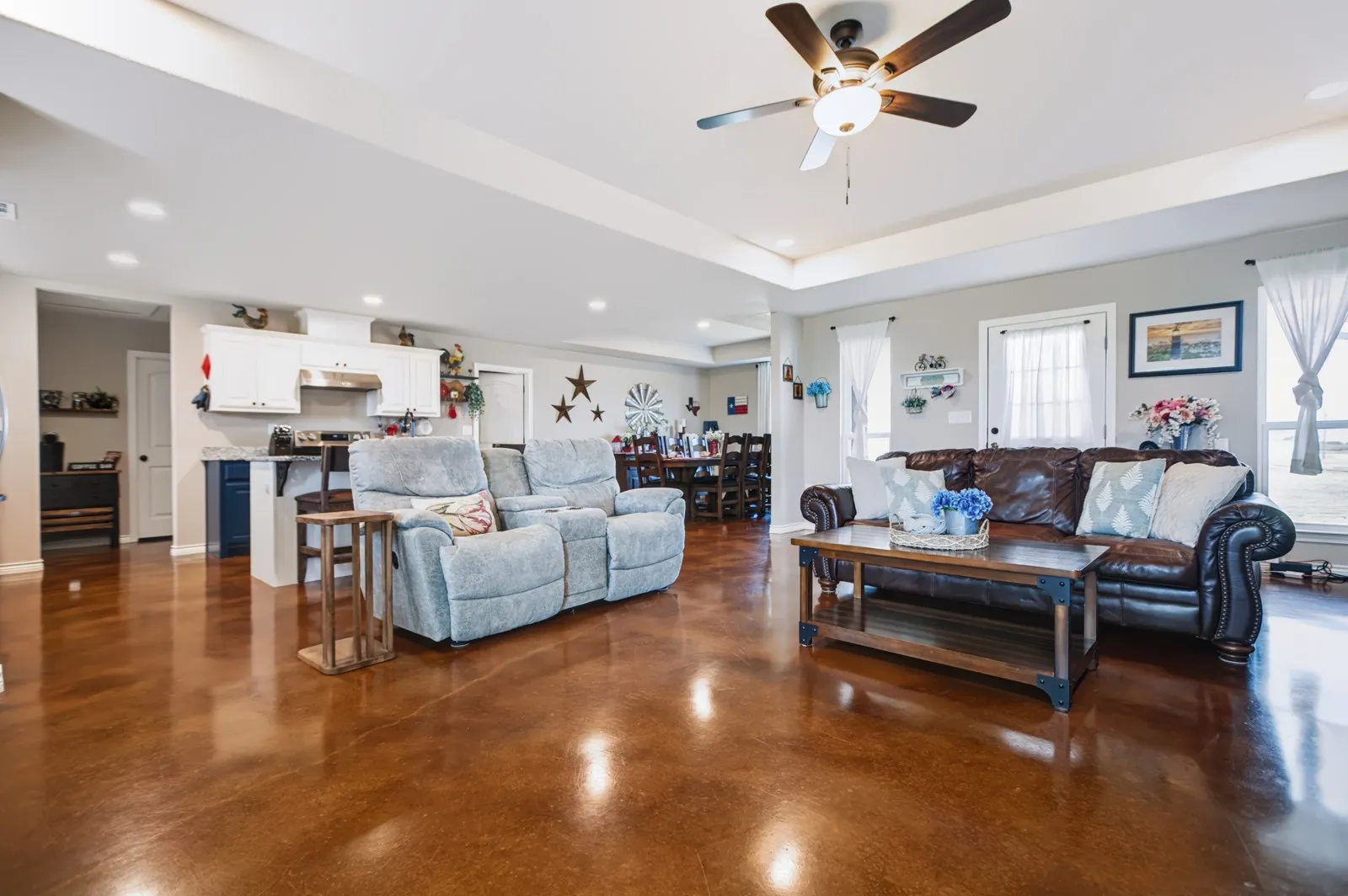 Open-concept living area with tray ceiling, ceiling fan, and recessed lighting