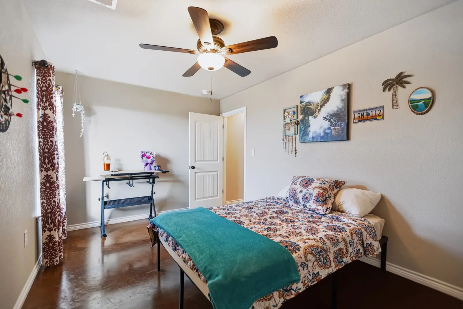 Guest Room 3
Smooth concrete flooring, ceiling fan with integrated lighting, white interior door, and neutral wall tones