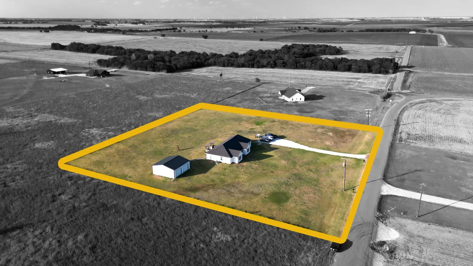 Expansive rural property featuring a main residence, detached outbuilding, and a long driveway
