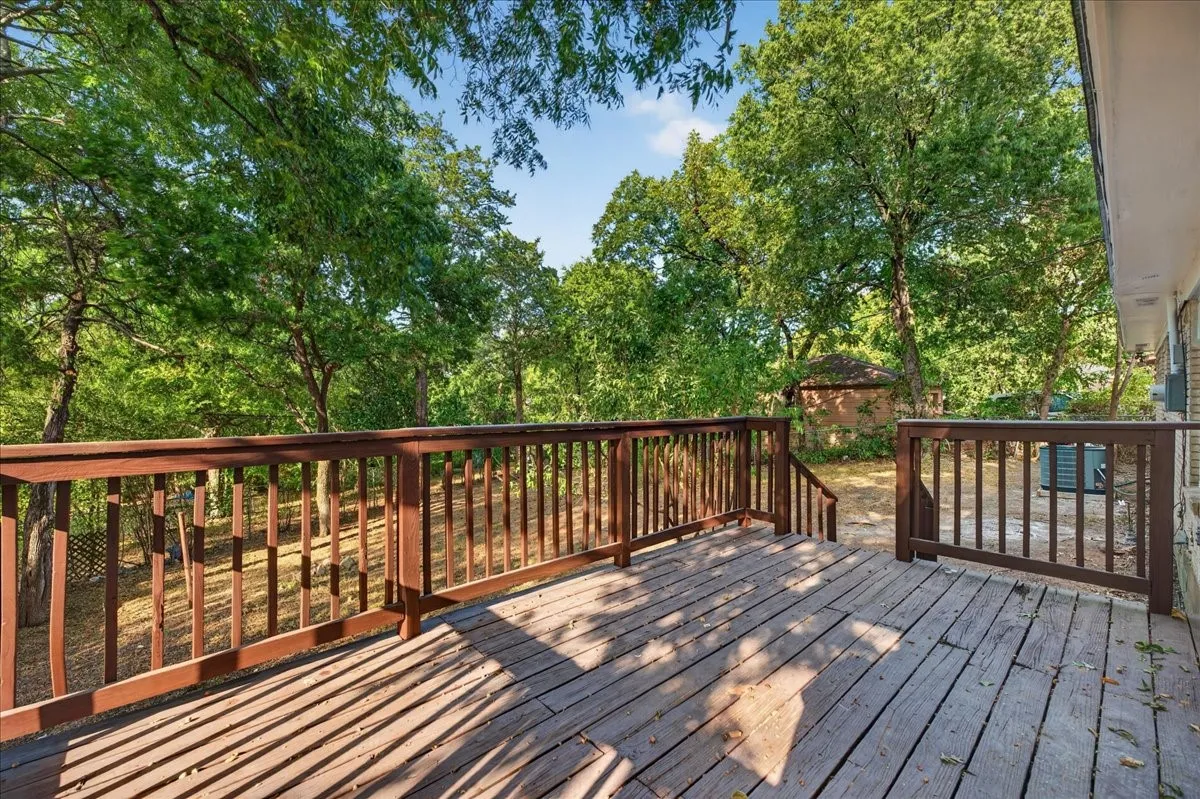 Expansive wood deck with rich-toned railings, offering a private outdoor extension surrounded by mature trees