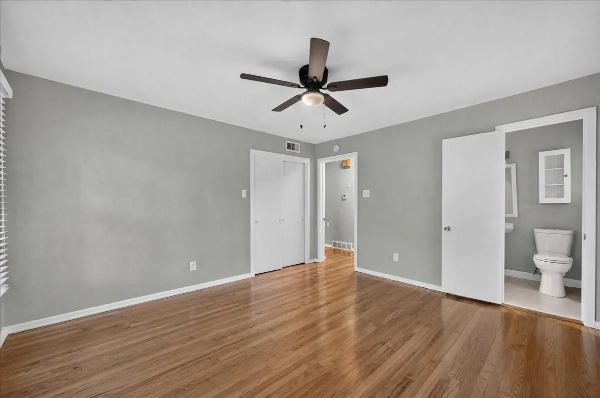 Hardwood flooring, ceiling fan with light fixture, double closet doors, white interior doors, and window with blinds