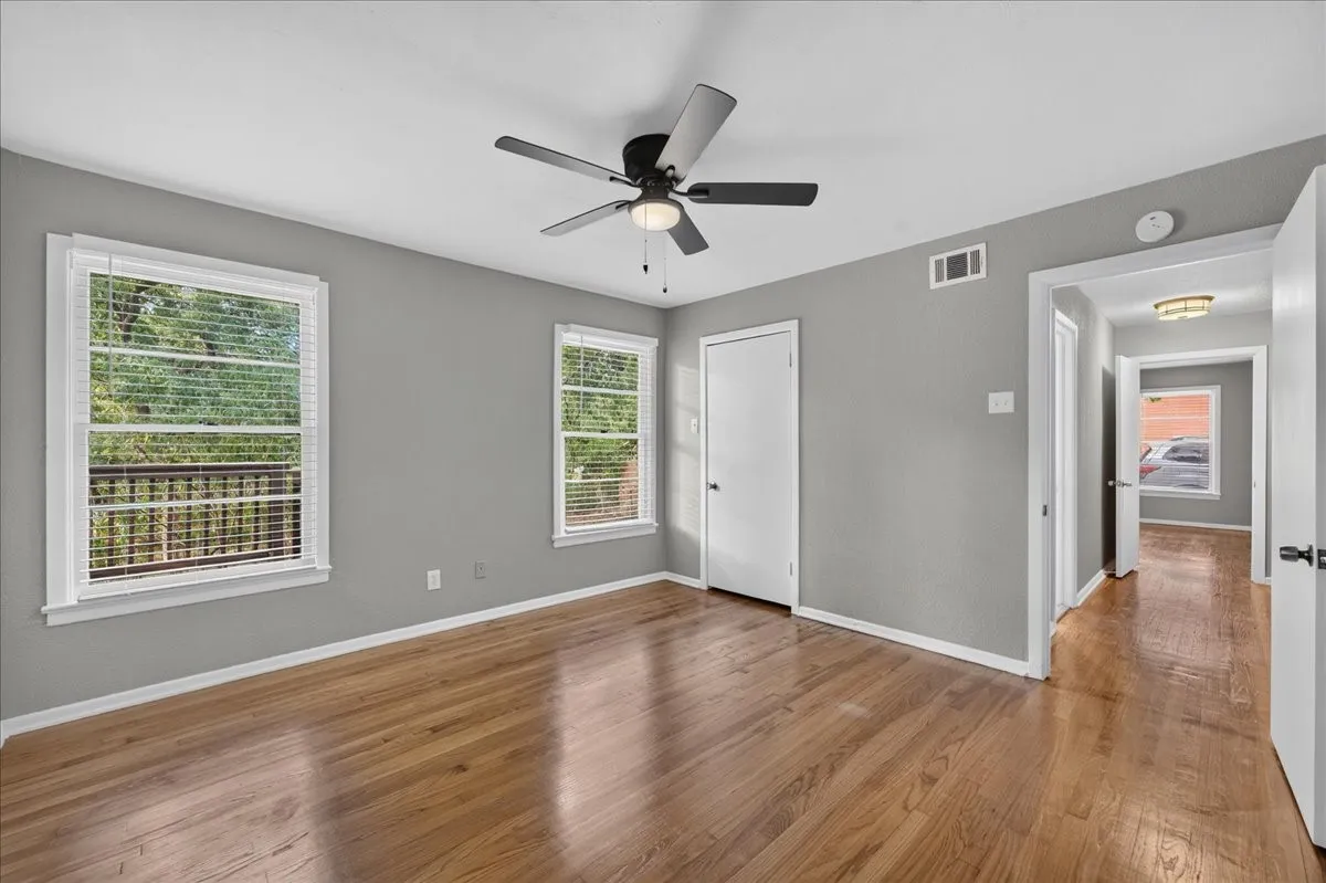 Hardwood flooring, painted walls, ceiling fan with light fixture, and multiple windows