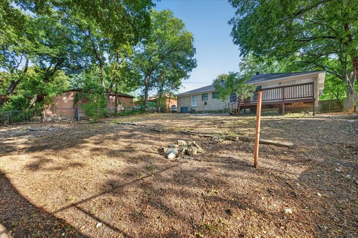 Expansive outdoor space featuring a raised wooden deck and mature trees