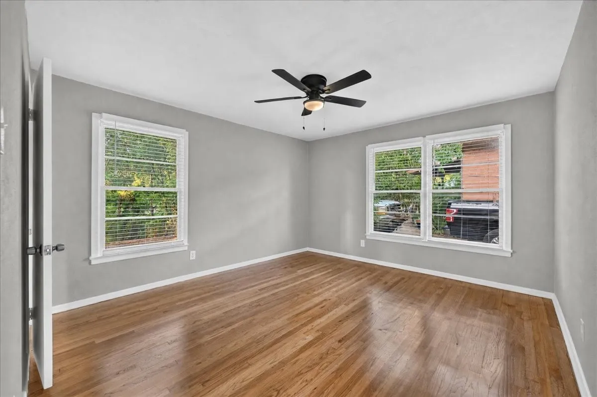 Hardwood flooring, painted walls, white trim, multiple windows, ceiling fan with integrated lighting