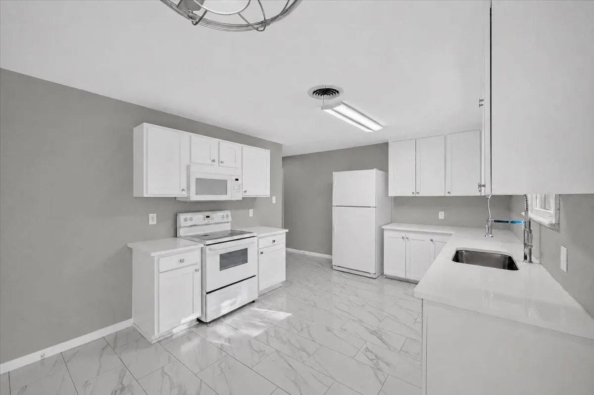 White cabinetry, white appliances, white countertops, tile flooring, and a stainless steel sink