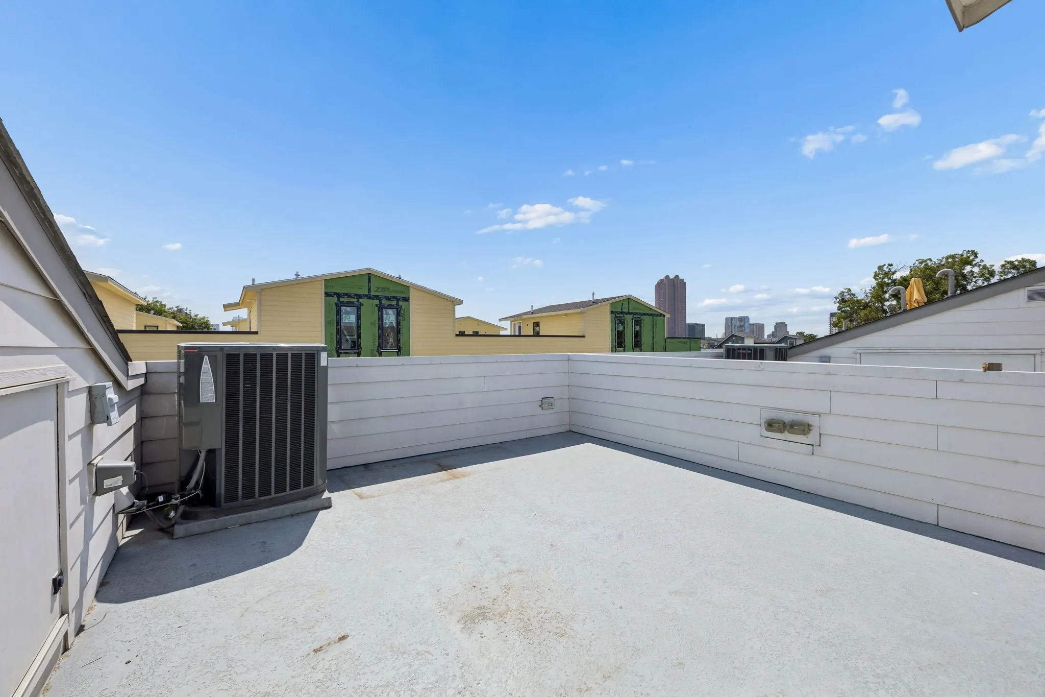 Rooftop deck featuring a light gray surface and white siding, with a cityscape backdrop