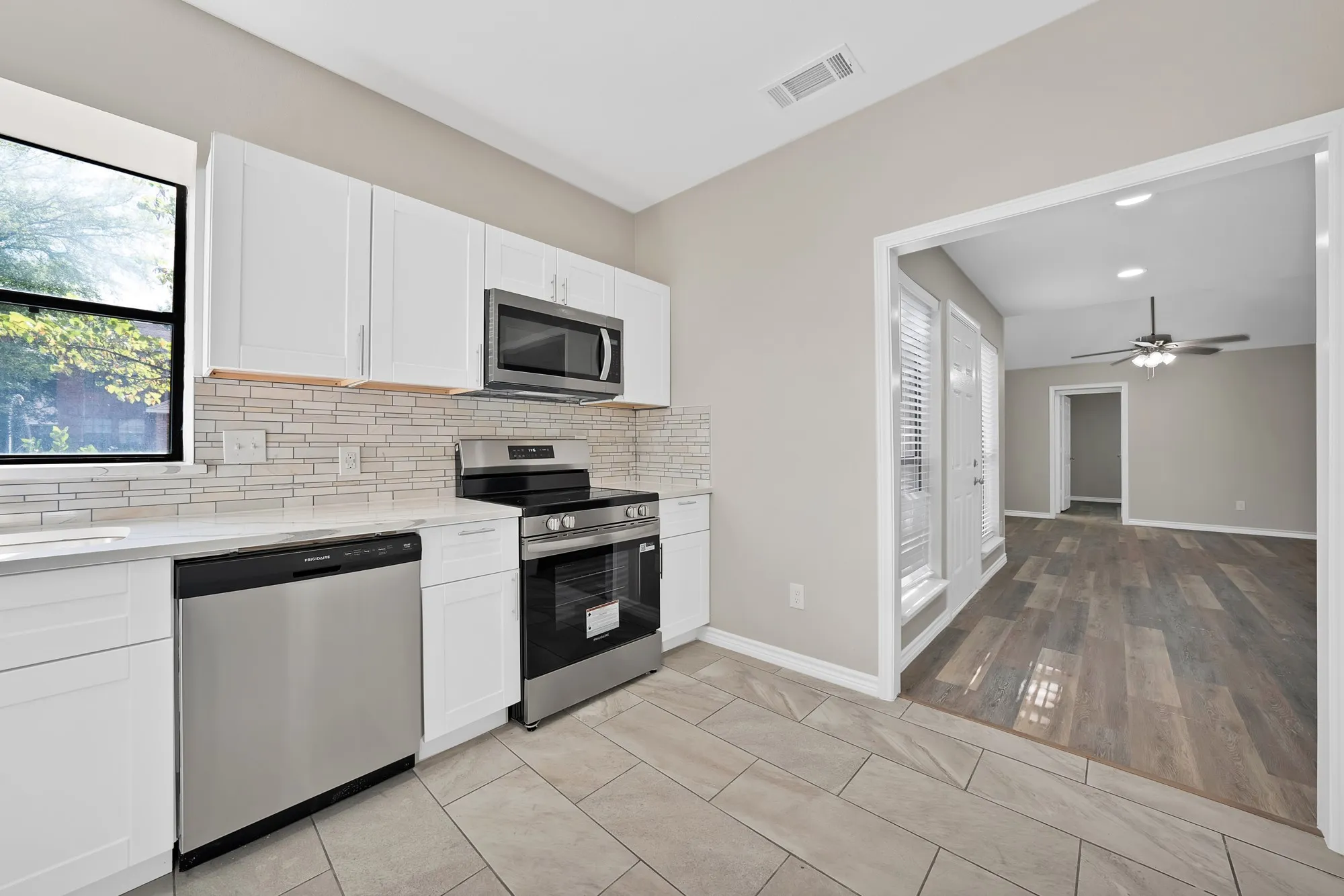 Contemporary kitchen featuring stainless steel appliances, white cabinetry, a tile backsplash, and light-toned countertops