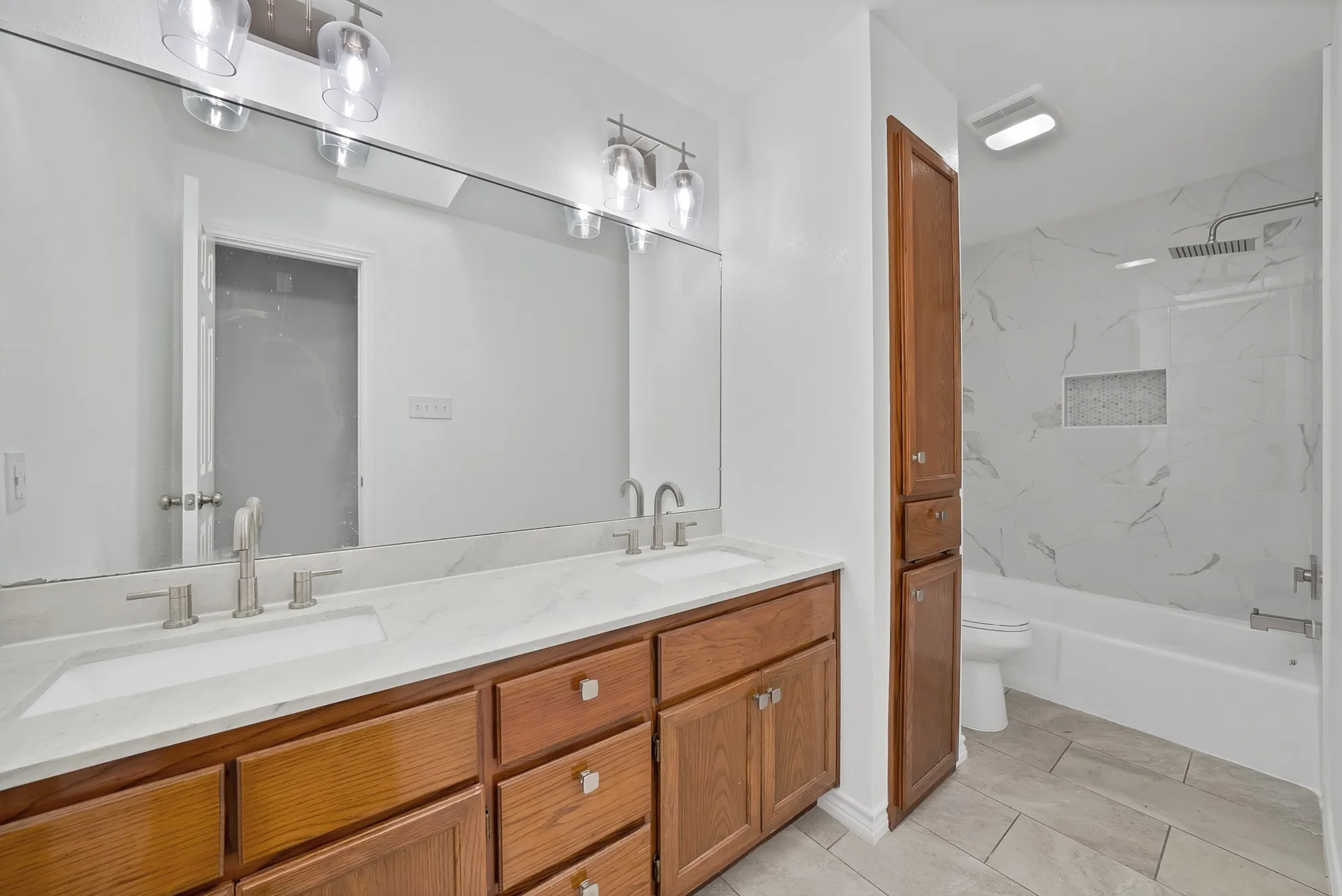 Dual vanity with integrated sinks, brushed nickel fixtures, and a spacious mirror