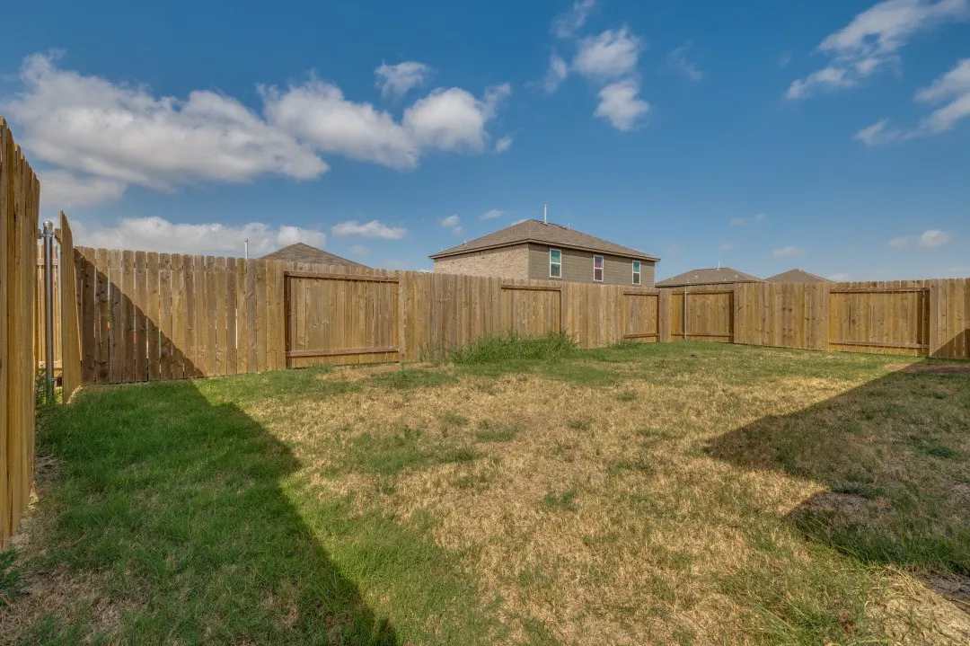 Enclosed backyard featuring wood fencing and an access gate