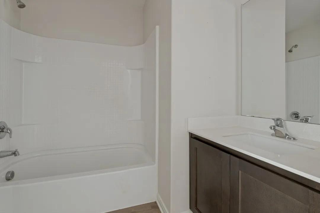 Tub and shower combination with a textured surround, single vanity with a white countertop, and an integrated sink