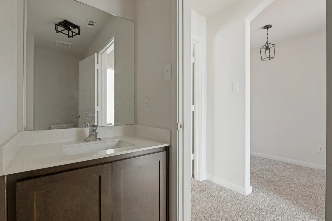 White countertop vanity with an undermount sink, dark wood-finish cabinetry, and a framed mirror